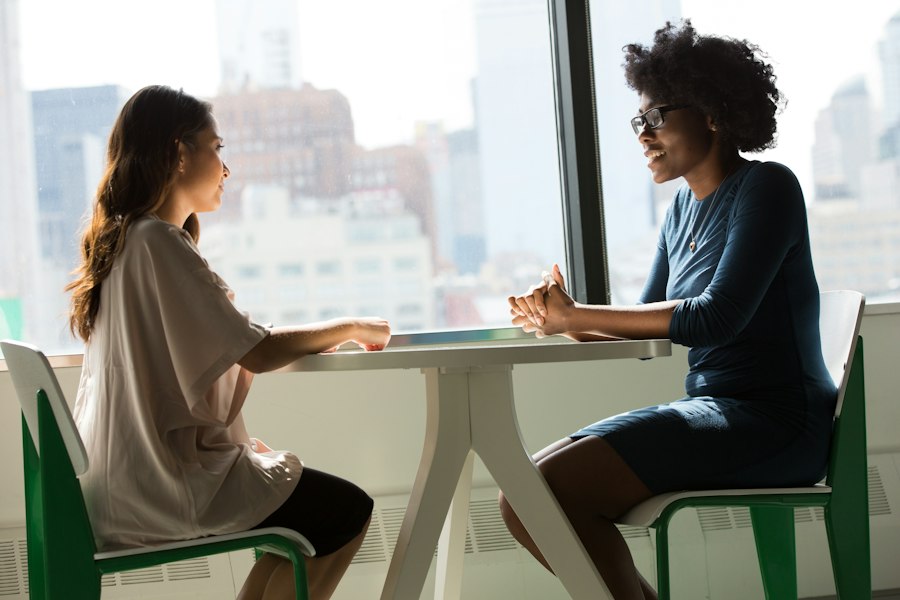 Two people talking across a table in a bright, calm room